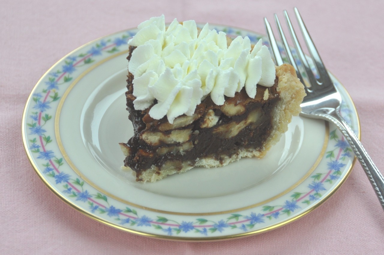 Traditional pecan pie made more delicious with chocolate and orange and topped with whipped cream.